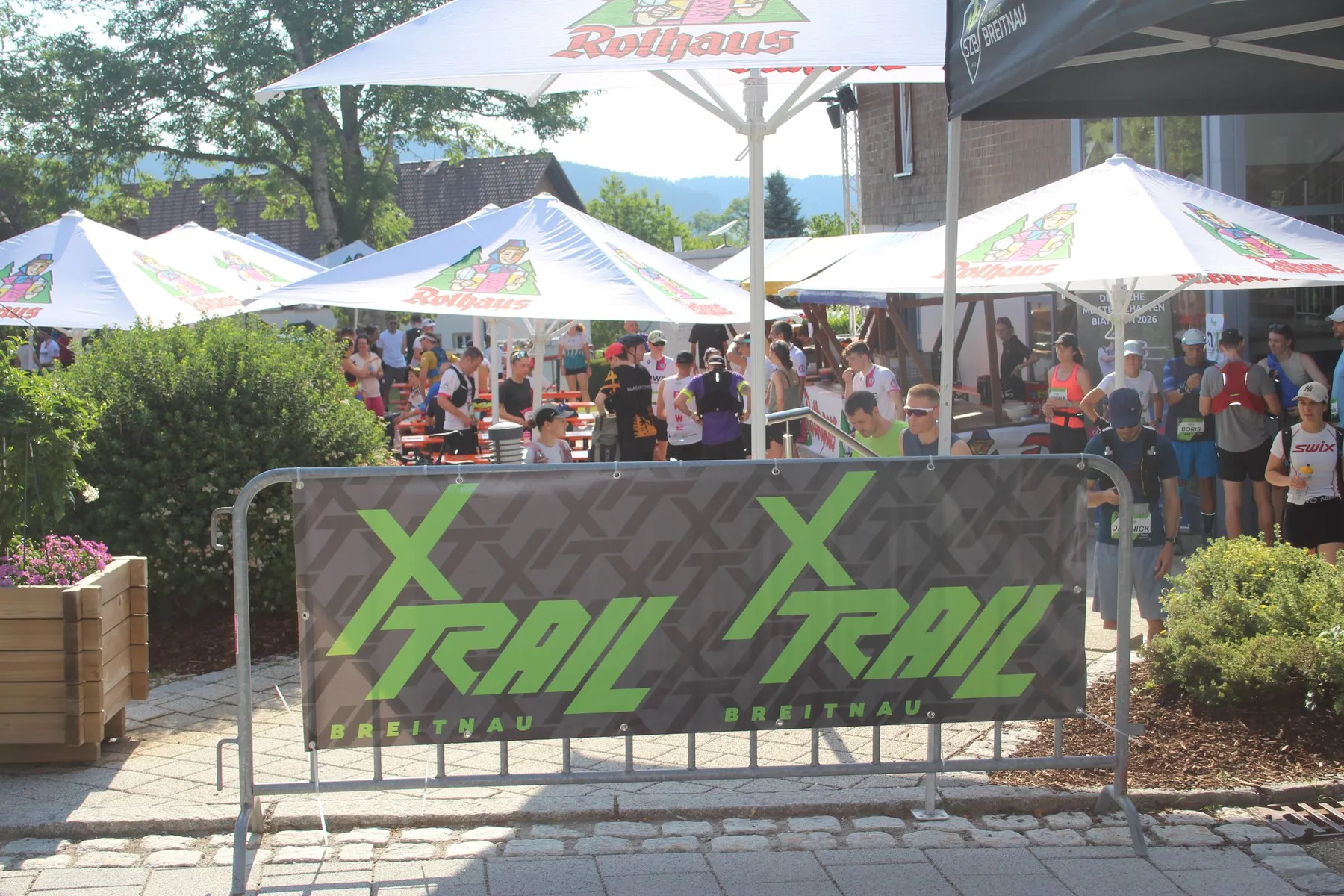 Start des X-Trail in Breitnau: Läuferinnen und Läufer mit Startnummern warten vor der Versorgungsstation unter Sonnenschirmen